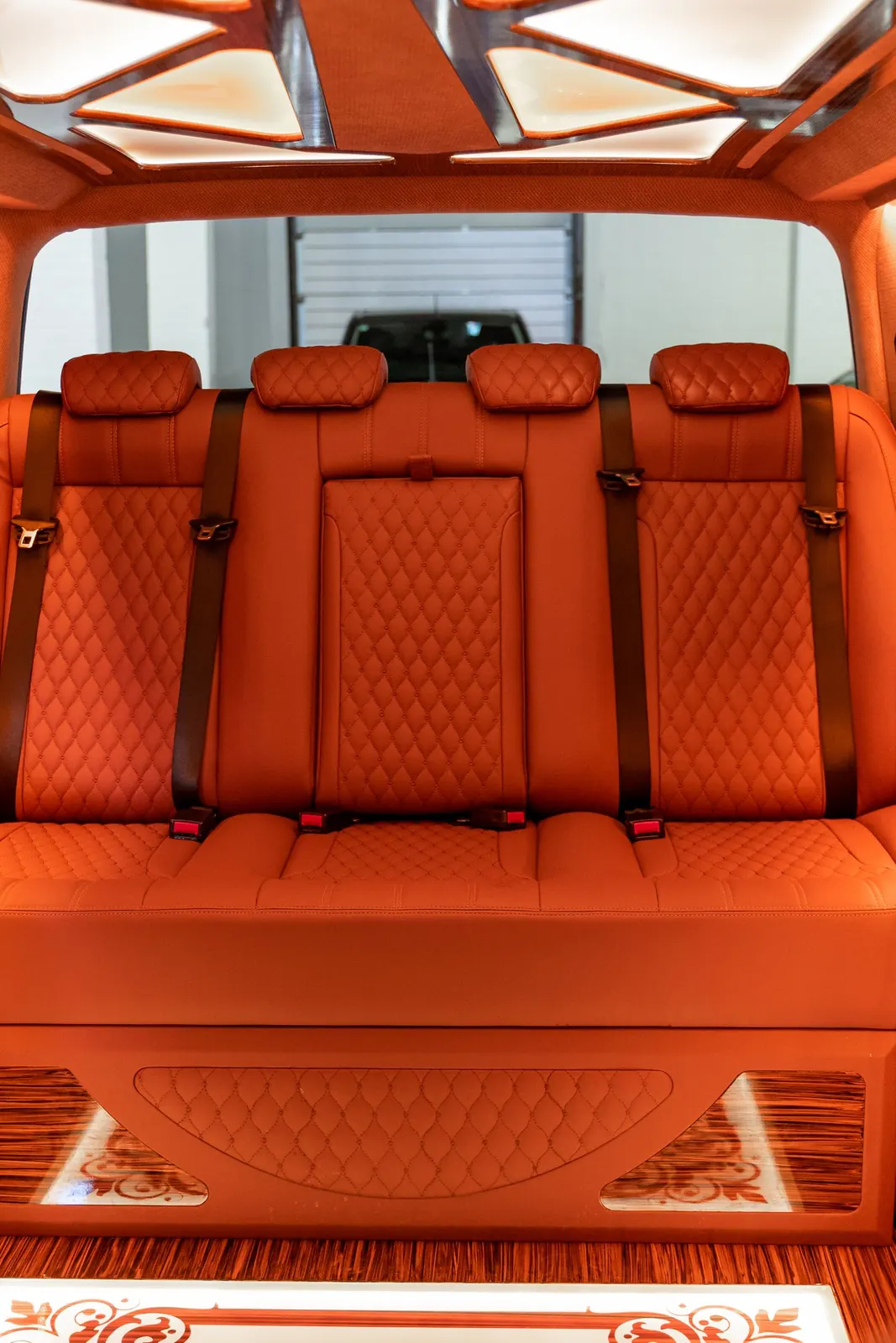 Interior de un carro con asientos traseros de cuero acolchado rojo-naranja, sin logos visibles