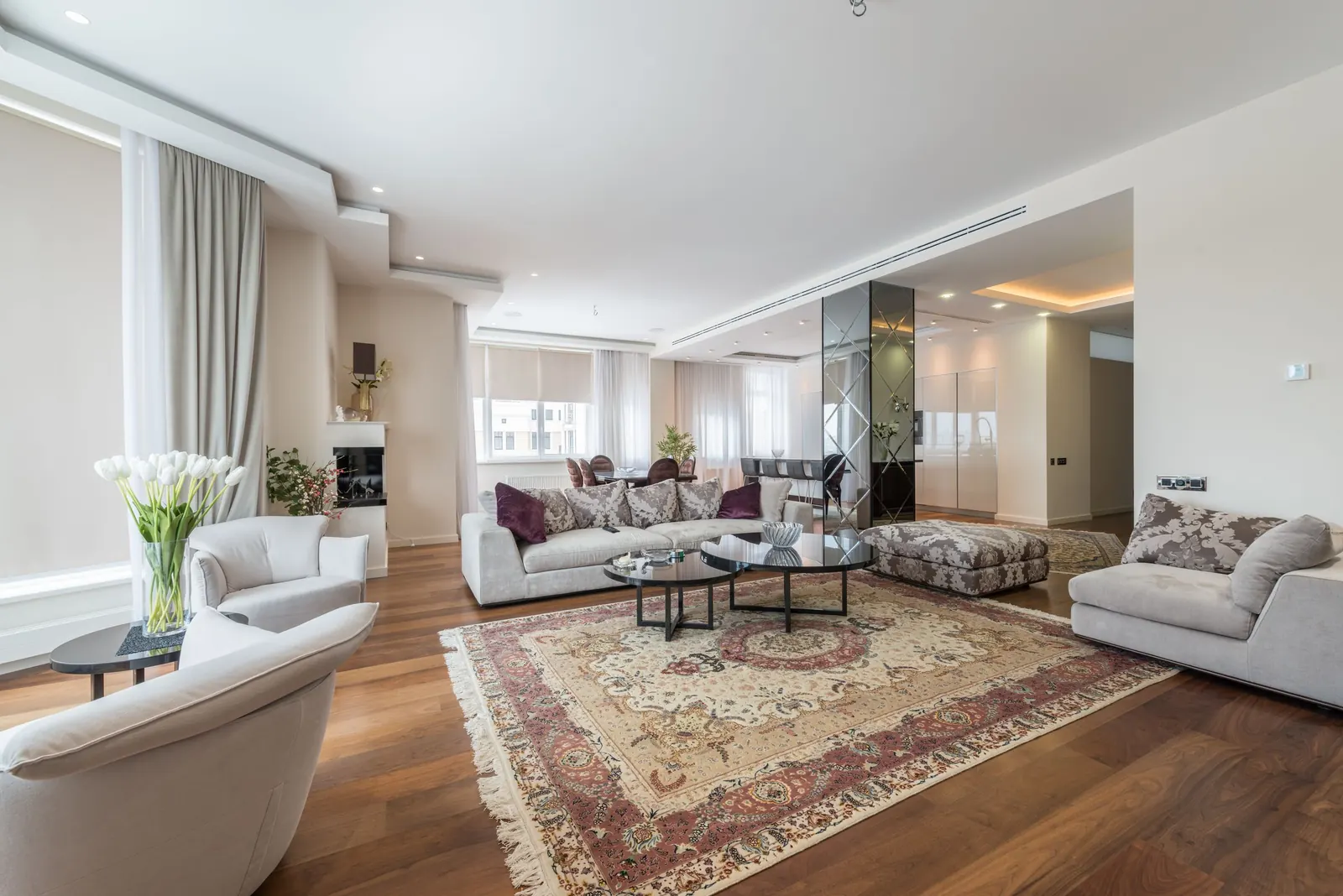 Sala amplia y luminosa de apartamento de lujo en tonos crema con alfombra clásica