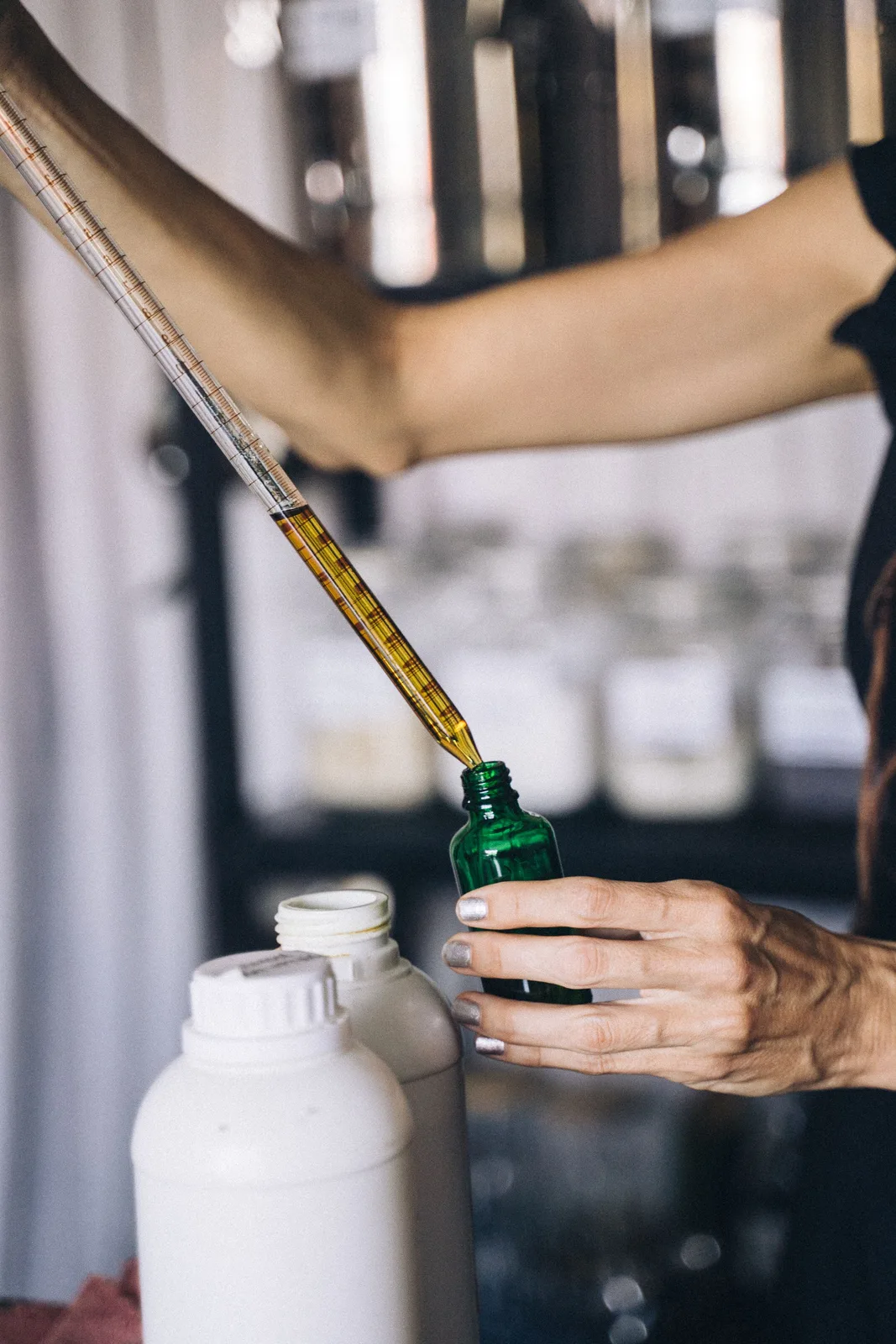 Manos recargando un frasco verde con una pipeta